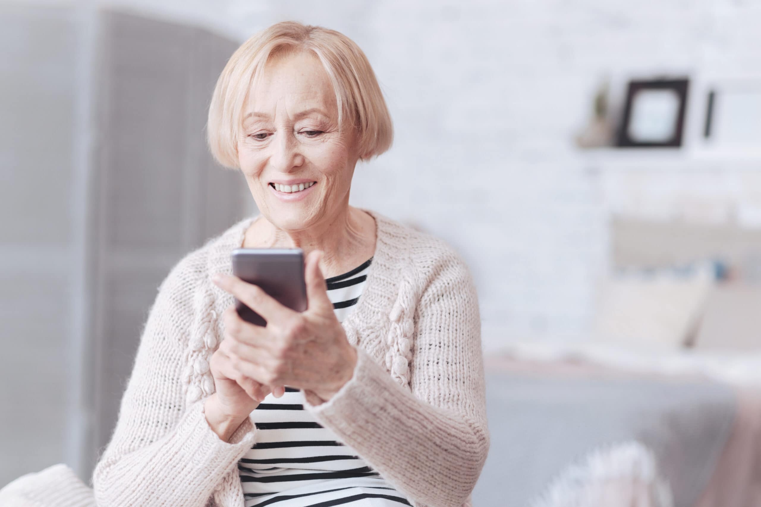 Positive minded senior lady looking at screen of her smartphone